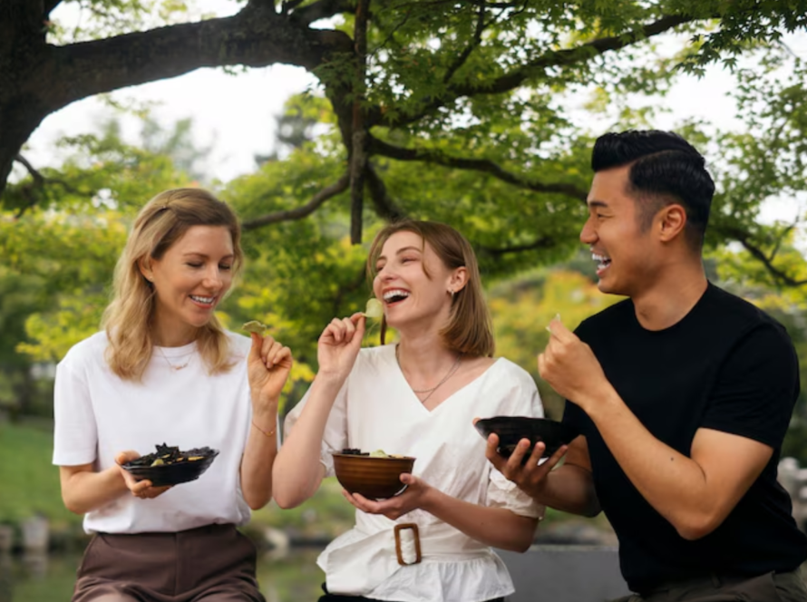 Three friends laughing while eating leafy greens together