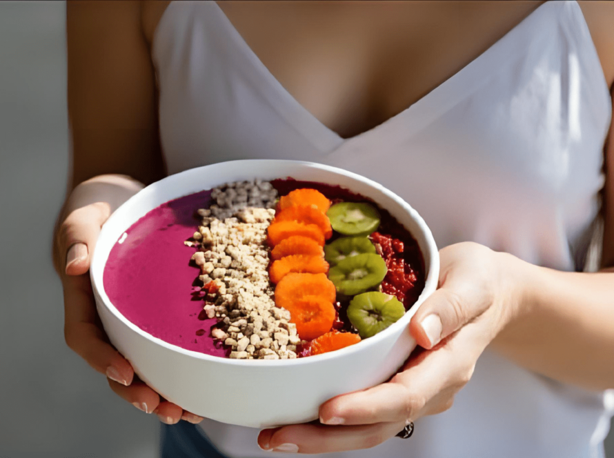 Woman holding smoothie bowl with fruit toppings